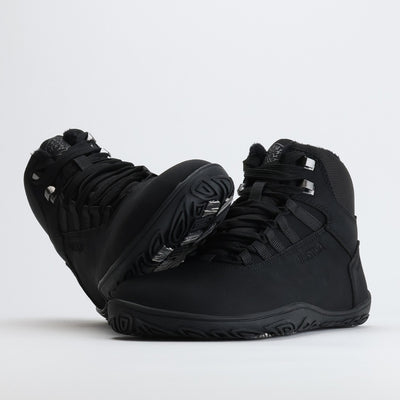 Noenmusta Vaistoa Uoma Talvi 3 -kenkäpari, jossa toinen kenkä nojaa toisen varvastilaan. Kuvassa korostuu leveä anatominen varvastila ja pitävä pohja.