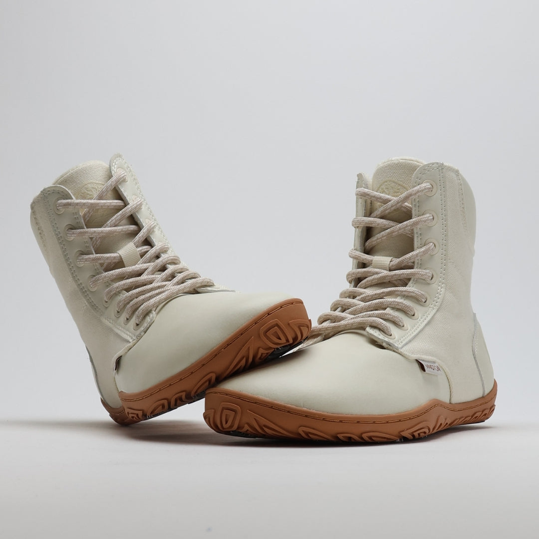 Luonnonvalkea Vaistoa Hurmos 2 -paljasjalkamaiharipari kuvattuna studiossa. Toinen kenkä nojaa toisen varvastilaan, ja kuvakulma korostaa kengän leveää muotoa ja joustavaa pohjaa.