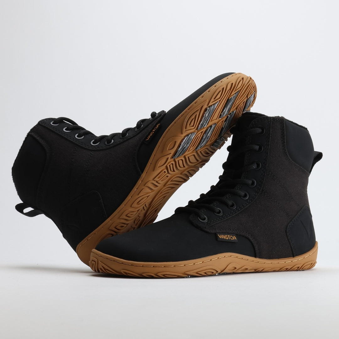 Musta Vaistoa Hurmos 2 -paljasjalkamaiharipari, jossa toinen kenkä nojaa toiseen. Kuvassa näkyy selkeästi pohjan kitkapalat ja joustava rakenne.